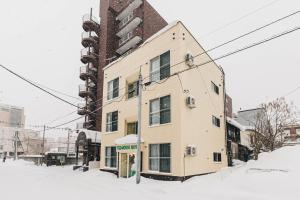 Un bâtiment dans la neige dans une rue dans l'établissement TKD HOUSE Asahikawa, à Asahikawa