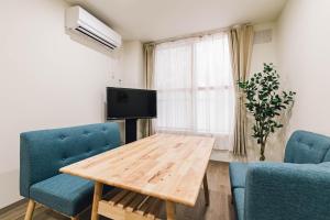 a living room with a wooden table and blue chairs at TKD HOUSE Asahikawa in Asahikawa
