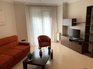 sala de estar con sofá, silla y TV en Apartamentos Illa en Isla de Arosa