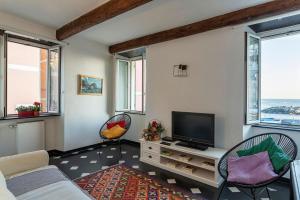 een woonkamer met een televisie en 2 stoelen bij Creuza de Ma by Wonderful Italy in Genua