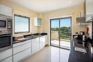 a kitchen with white cabinets and a large window at Shantiapartments in Vilamoura