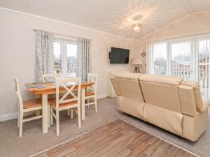 uma sala de jantar e sala de estar com uma mesa e um sofá em Duckling Lodge em Carnforth