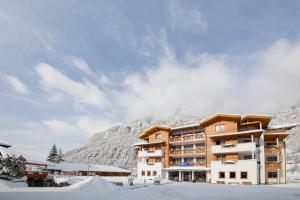 a building in the snow with a mountain in the background at Residence Nele in Ziano di Fiemme