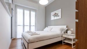 - une chambre blanche avec un grand lit et une fenêtre dans l'établissement Italianway - Palladio 16, à Milan