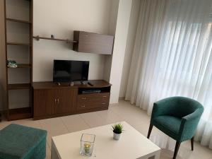 sala de estar con TV, silla y mesa en Apartamentos Arosa, en A Illa de Arousa