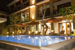 a swimming pool in front of a building with umbrellas at D Sarian Seminyak in Seminyak