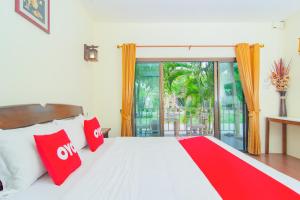 a bedroom with a bed with red pillows and a window at OYO 607 Nawang Resort in Hua Hin