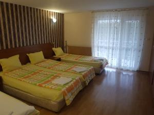 two beds in a hotel room with a window at Hotel Zora in Velingrad