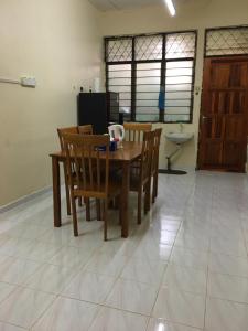 a dining room with a wooden table and chairs at Homestay Abdul in Kampung Banggul Gucil