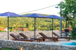 um grupo de cadeiras e guarda-sóis ao lado de uma piscina em Villa Novak em Cilipi