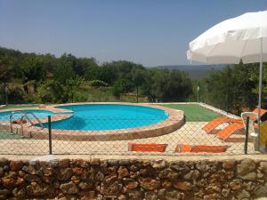 - une piscine avec des chaises et un parasol dans l'établissement Casa Do Forno - Quinta Amoreira, à Faro