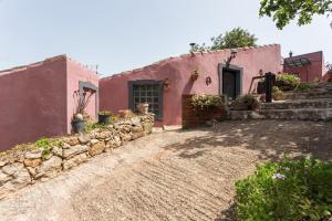 ein rosafarbenes Haus mit einer Steinmauer in der Unterkunft Casa Do Forno - Quinta Amoreira in Faro