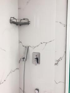 een badkamer met een witte muur en een lichtschakelaar bij Omiros in Faliraki