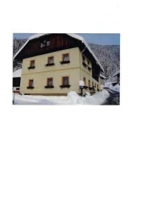 a building with a snow covered roof in the snow at Haus Stöffler in Reisach