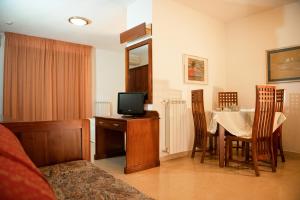 a room with a table, chairs and a television at Hotel Califfo in Quartu SantʼElena