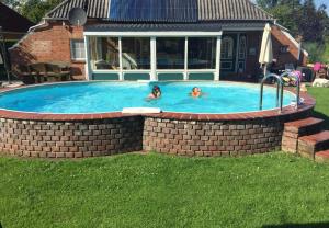 two people swimming in a brick swimming pool at Ferienhof Welsch Wohnung 2 in Großefehn 