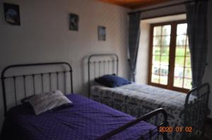 two beds in a bedroom with a window at Ma maison bleue in Saint-Brice-sous-Rânes