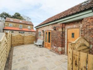 a patio with a bench and a brick building at The Hayloft in Husthwaite
