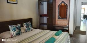 - une chambre avec un lit doté d'oreillers verts et d'un miroir dans l'établissement Hotel Bonanza, à Baga