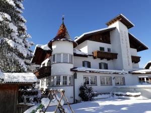 a large white house with a snow covered roof at Hotel Pörnbacher in Valdaora