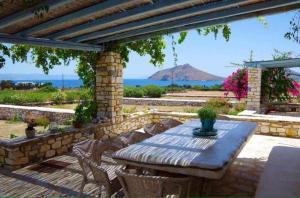 a patio with a table and chairs and a stone wall at Villa Petradi (150 meters from the sea) in Ambelas