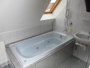 a bathroom with a bath tub and a sink at Apartmenthaus Am Schlosspark in Schkopau +59 photos