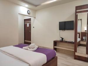 a bedroom with a bed and a tv on a wall at Hotel Grand Ganesha in Ganpatipule