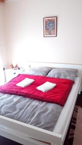 a bed with two white towels on a red blanket at Sobe i apartmani Lipa 12 in Repušnica +15 photos