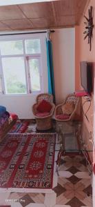 ein Wohnzimmer mit Tisch und Stühlen und einem Fernseher in der Unterkunft Shanti Jungle cottage in Mashobra