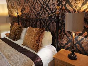 Glangwili Mansion - Luxury 5 star Bed & Breakfast في كرمرثن: غرفة نوم بسرير ومصباحين على طاولة