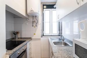 a white kitchen with a sink and a window at FLH Bica Charming Flat in Lisbon