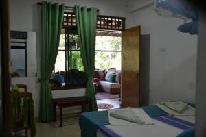 Habitación con 2 camas y ventana con cortinas verdes. en Green Woods, en Kandy