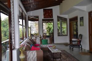 sala de estar con sofá y algunas ventanas en Green Woods, en Kandy
