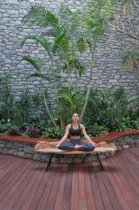 a woman is sitting in a yoga position on a bench at Les Suites at The Cliff Bay - PortoBay in Funchal