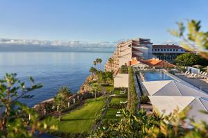 a view of a resort with a pool and the ocean at Les Suites at The Cliff Bay - PortoBay in Funchal