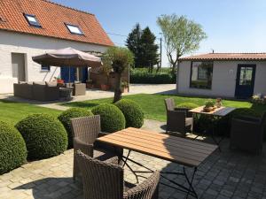 a patio with a table and chairs and an umbrella at 'T Wolvennest in Heuvelland