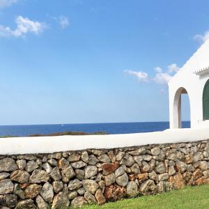 een stenen muur voor een kerk en de oceaan bij BiniBridge in Binibeca