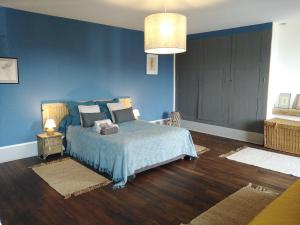 a bedroom with a bed with blue walls and wooden floors at Meublé de tourisme La Maison d'Orgy in Chevannes