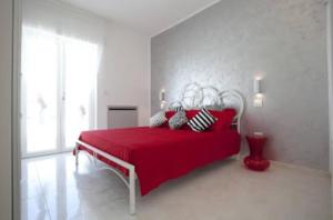 a white bedroom with a red bed with a redspread at Attico Diamante in Gallipoli