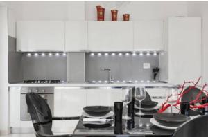 a kitchen with white cabinets and a table with plates at Attico Diamante in Gallipoli