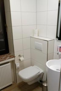 a white bathroom with a toilet and a sink at Hotel Restaurant Rodizio Paderborn in Altenbeken