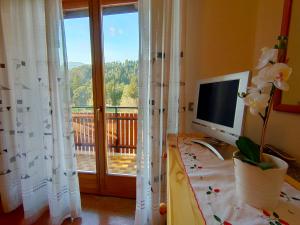 a desk with a computer and a window with a balcony at Appartamenti Pedrini in Comano Terme
