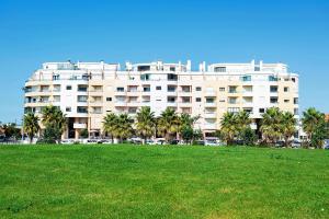 ein großes Gebäude mit Palmen vor einem Grasfeld in der Unterkunft Hoso Apartments T1 in Costa da Caparica