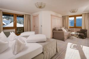 a bedroom with two beds and a living room with a couch at Wellnesshotel Cervosa in Serfaus