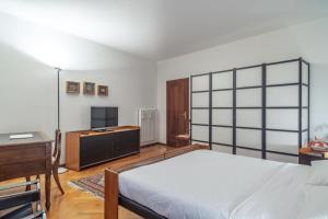 a bedroom with a bed and a desk and a tv at Casa Mathilda in Trento