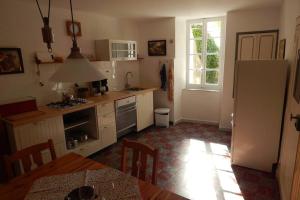 a kitchen with a table and a refrigerator and a window at Gemütliches altes Landhaus in Alaigne