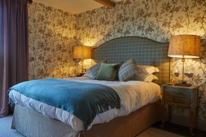 a bedroom with a large bed with a blue blanket at The Duncombe Arms in Ellastone