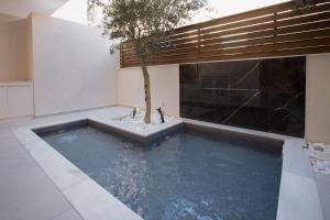uma piscina com uma árvore no meio de uma casa em Acropolis Golden Suites by GHH em Atenas