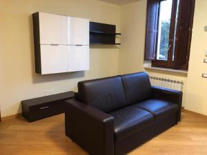 a black leather couch in a living room with a cabinet at FORT.Montagna A106 in Rivisondoli +5 photos
