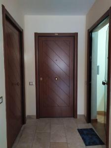 - un couloir avec deux portes en bois et du carrelage dans l'établissement FORT.Montagna A106, à Rivisondoli